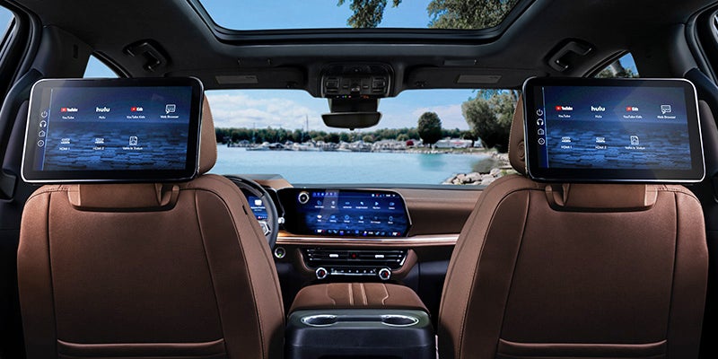 Rear cabin view of a premium SUV featuring dual rear-seat entertainment screens, panoramic sunroof