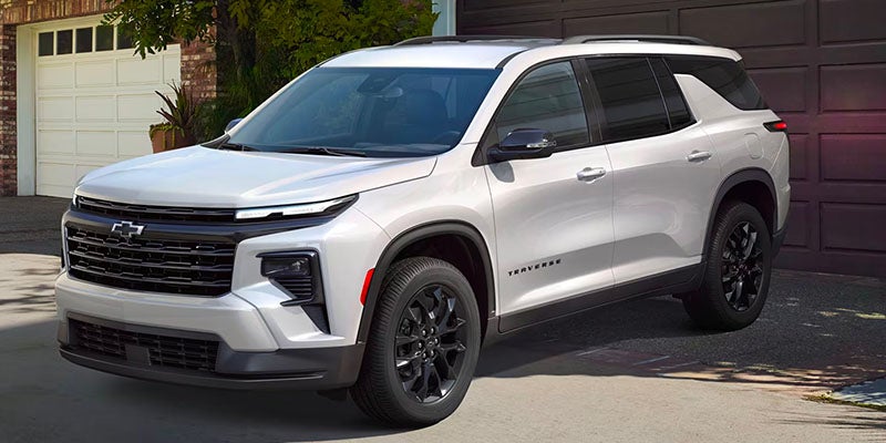 White Chevrolet Traverse SUV parked on a driveway in front of a garage