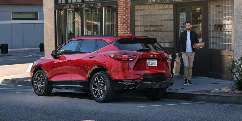 Rear three-quarter view of a red Chevrolet Blazer SUV parked along a city street outside storefronts