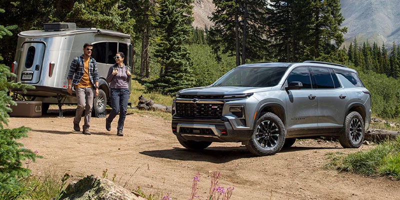 2027 Chevrolet Traverse parked outdoors with a camper trailer and family nearby