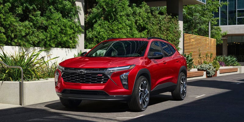 Red Chevrolet SUV parked on a city street beside landscaped greenery