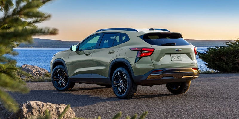 Rear three-quarter view of a light green compact SUV parked on a coastal roadway