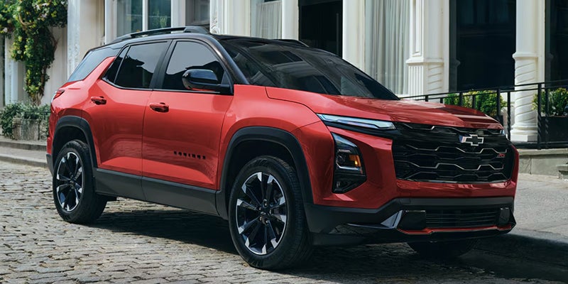 2027 Chevrolet Equinox EV in blue seen head-on with an illuminated front light bar beside a lake