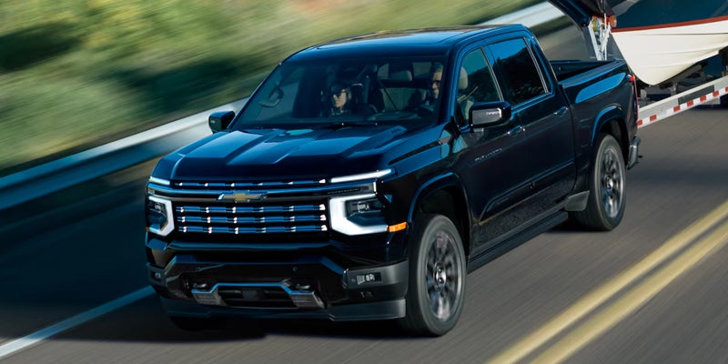 2027 Chevrolet Silverado 1500 towing a boat on the highway