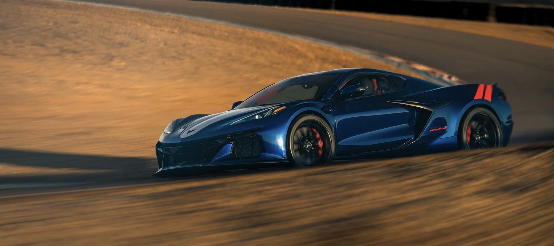 2027 Chevrolet Corvette Grand Sport in blue, dynamic side view on racetrack banking