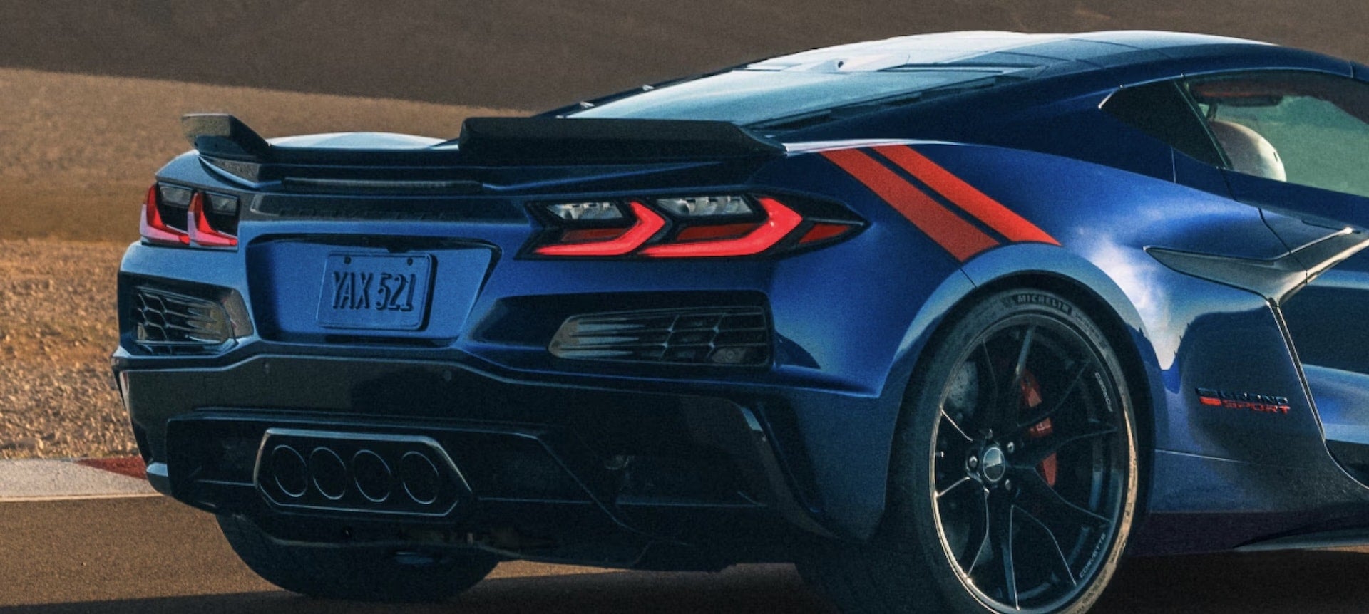 2027 Chevrolet Corvette Grand Sport rear view close-up with quad exhaust and orange stripes