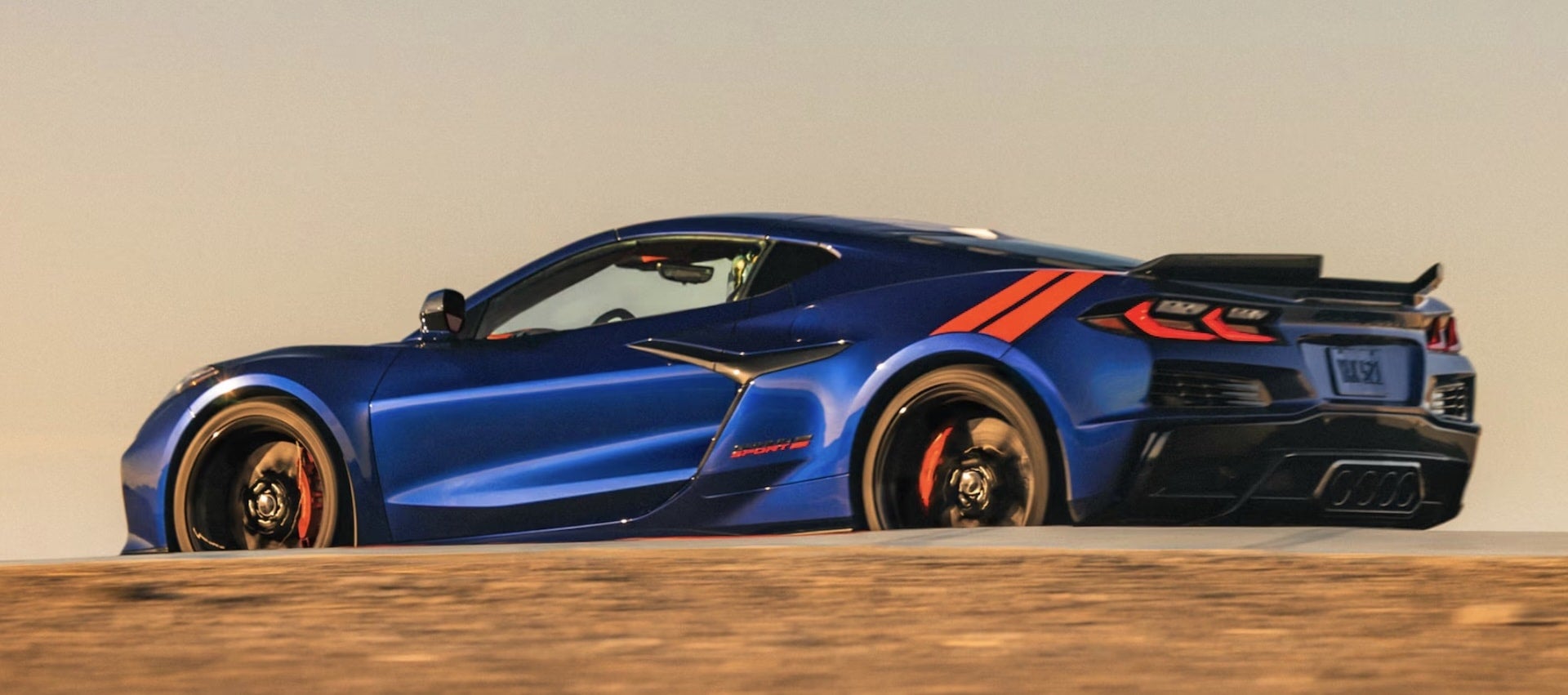 2027 Chevrolet Corvette Grand Sport in blue, side profile with orange racing stripes and rear wing