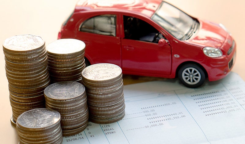 Stacks of coins next to a small red toy car